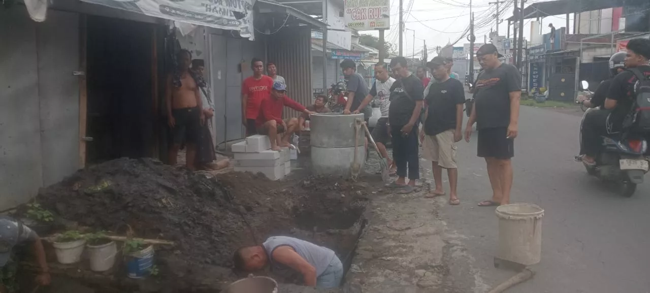 Warga RT 25 RW 07 Dusun Sungon, Desa Suko, Kecamatan Sidoarjo, turun tangan memperbaiki saluran air yang tersumbat melalui aksi gotong royong, Minggu (23/11/2025).