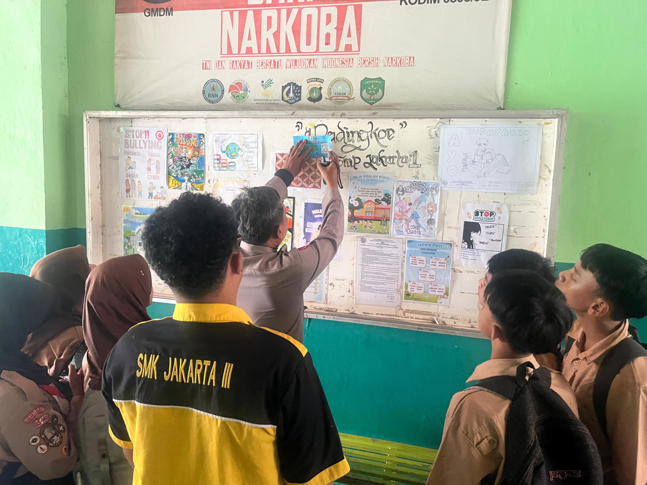 Petugas Polresta Jakarta Barat tengah menempelkan pengumuman di sekoah