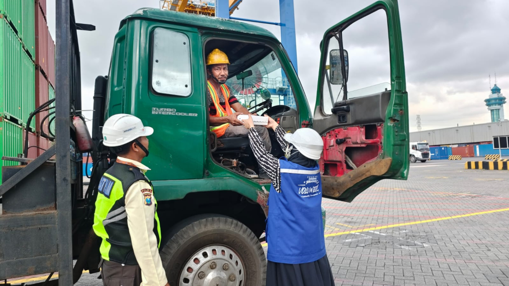 Salah satu pekerja TPS, Kamsiati, sedang memberikan paket makanan takjil kepada pengemudi truk eksternal pada Kamis (5-3) di area lapangan penumpukan TPS