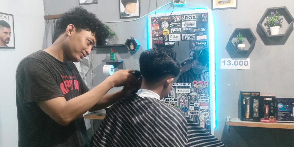 Keterangan foto: Agung (kiri), pemilik barbershop di Desa Dadaplangu, Kecamatan Ponggok, Kabupaten Blitar sedang melayani pelanggan. (Foto: Rio Rolis)