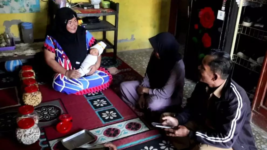 Yuharni kala menggendong Muhammad MBG Subianto di rumahnya Dusun Prigi, Desa Jolontoro, Kecamatan Sapuran, Kabupaten Wonosobo, Jawa Tengah. ( Foto tvonenews.com for JatimUPdate.id)